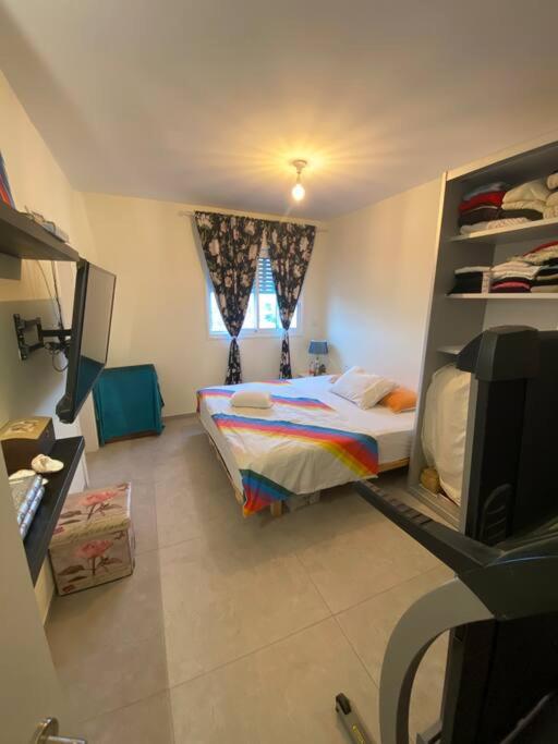 a small bedroom with a bed and a television at Dudger home in Yehud