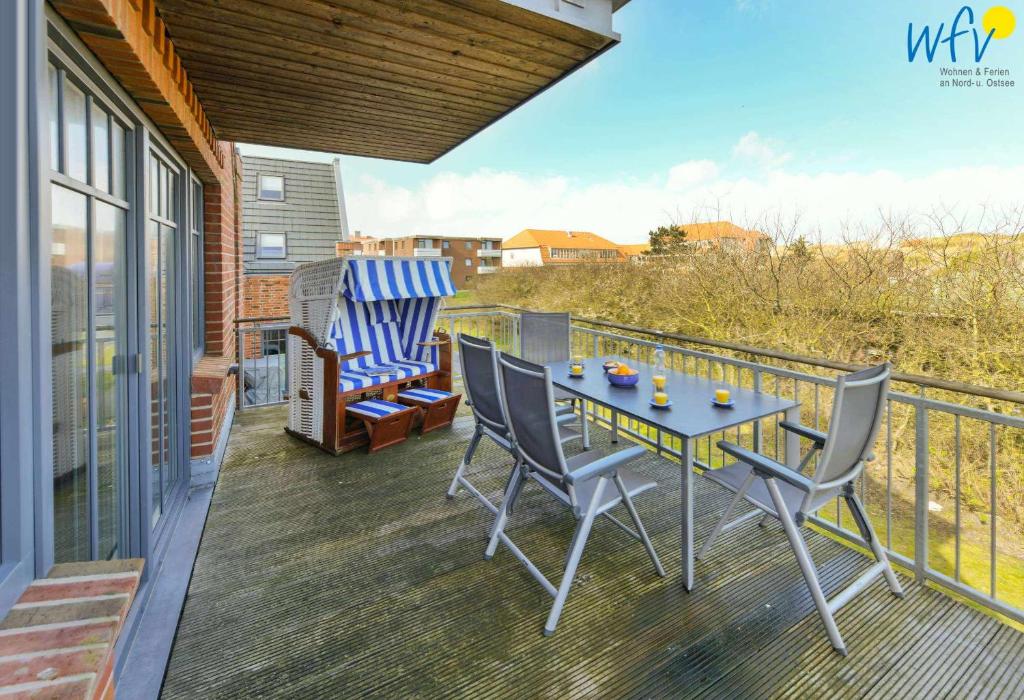 a patio with a table and chairs on a balcony at Bootshaus in den Duenen - 5 - "Ferienwohnung Strandgut" in Wangerooge