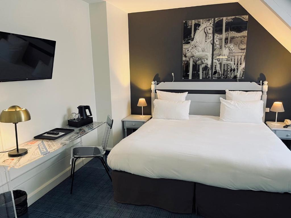 a hotel room with a large bed and a desk at Hotel Le Cardinal Rueil Centre in Rueil-Malmaison