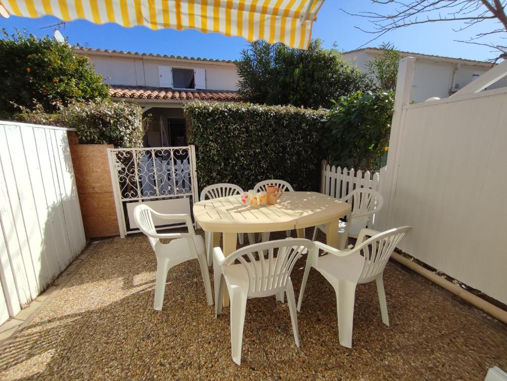 une table blanche et des chaises sur une terrasse dans l'établissement AZUR ET SOLEIL Jolie Maisonnette climatisée proche de la mer Richelieu Cap d'Agde, au Cap d'Agde