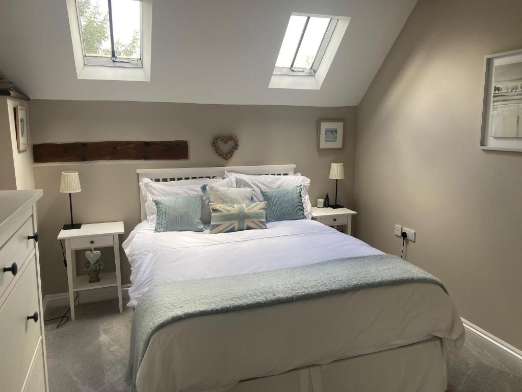 a bedroom with a large white bed with pillows at The Barn in Bishops Tachbrook