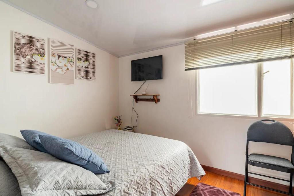 1 dormitorio con 1 cama, 1 silla y 1 ventana en Excelente ubicación, movistar, parque simon Bolivar, en Bogotá