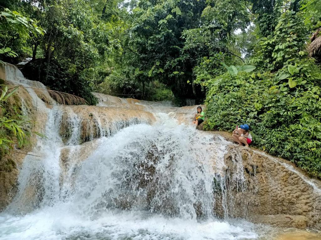a group of people sitting on top of a waterfall at Puluong homestay1holiday in Pu Luong