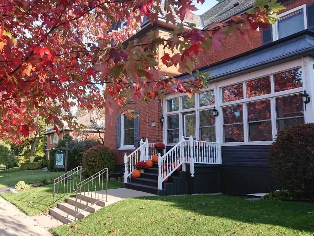 une maison en briques rouges avec une terrasse couverte blanche et des escaliers. dans l'établissement Colborne Bed and Breakfast, à Goderich