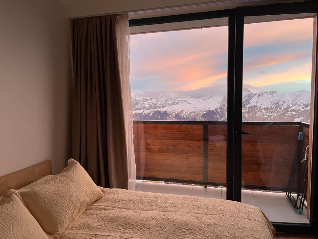 a bedroom with a bed and a large window with snow covered mountains at Twins #144 New Gudauri with Mountain View in Gudauri