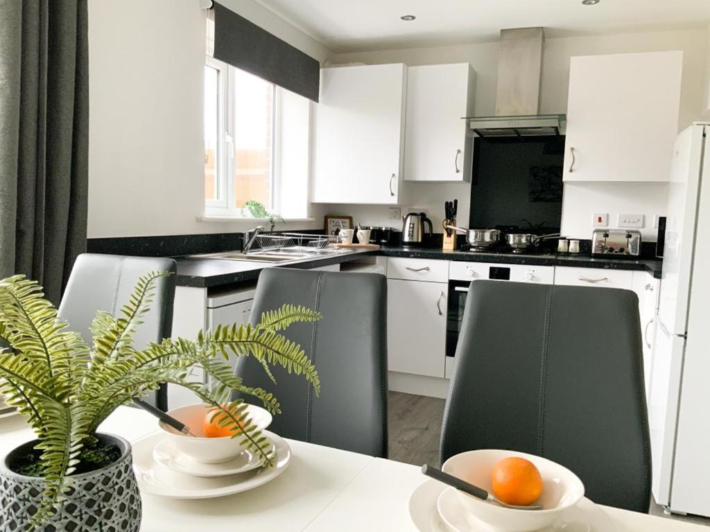 a kitchen with white cabinets and a table with a plant at Antley House in Andover