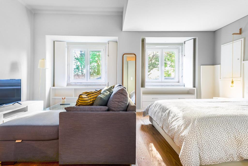 a bedroom with a bed and a couch and windows at Charming Studio in central Lisbon in Lisbon