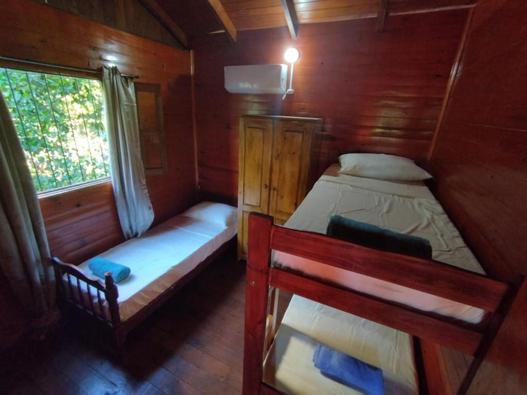a small room with two beds and a window at A la Vera del Río in Puerto Iguazú