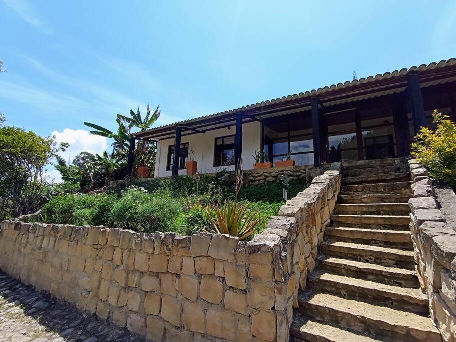 una casa con una pared de piedra y escaleras en Finca de descanso Amai Haru Jenesano en Jenesano