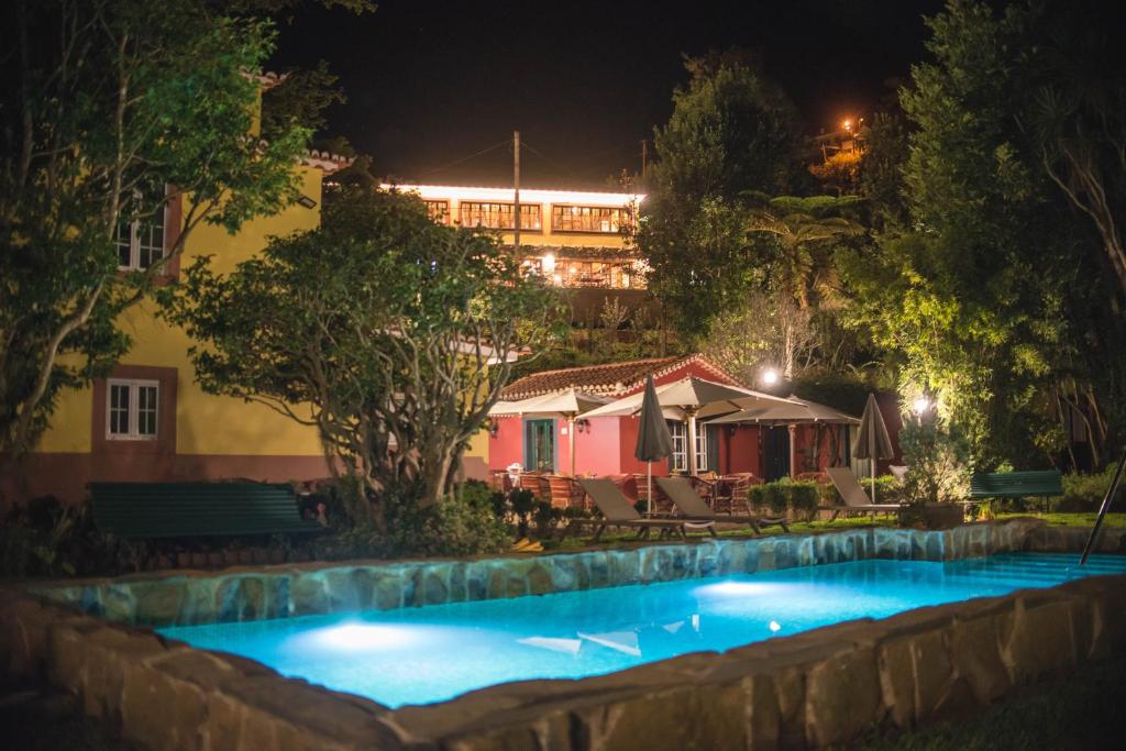 a swimming pool in front of a house at night at Quinta da Moscadinha in Camacha