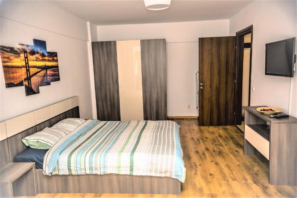 a bedroom with a bed and a desk and a television at Apartament Mamaia Nord in Mamaia Nord