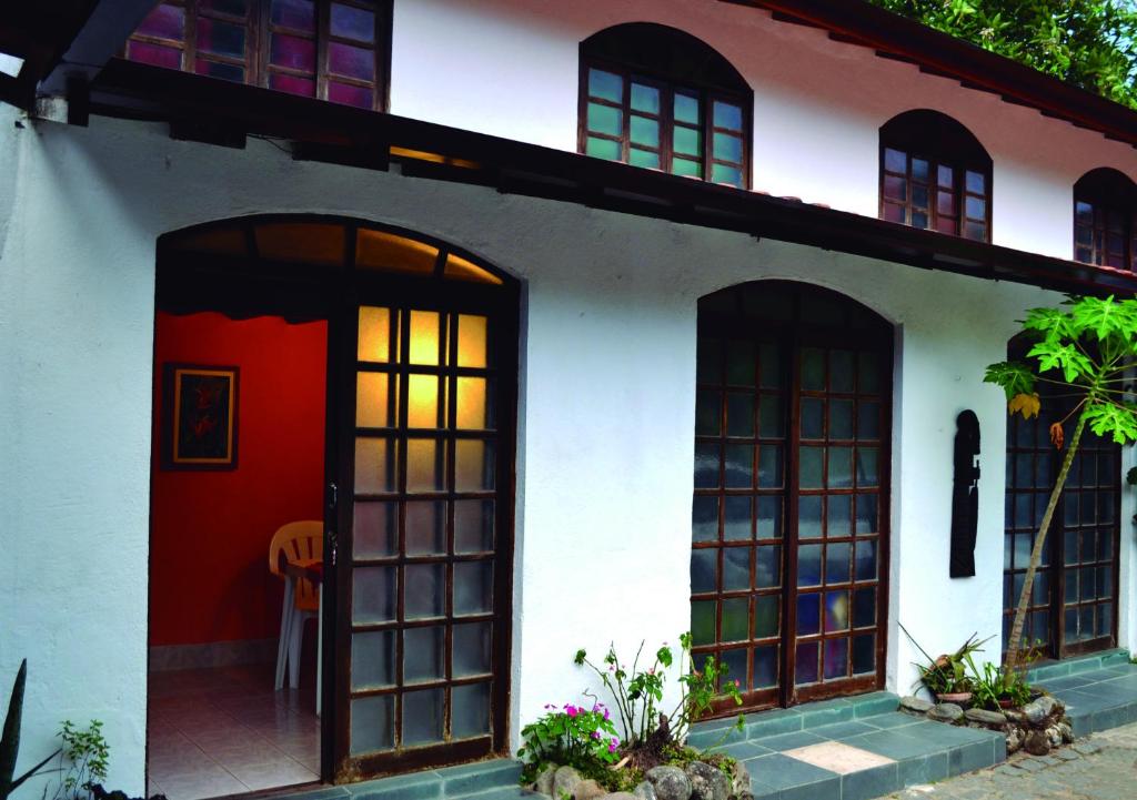 een wit huis met een rode deur en ramen bij Pousada Em Busca do Sol in Trindade