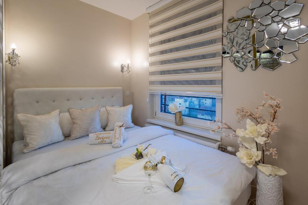 una camera da letto con un letto con lenzuola bianche e una finestra di Apartman Živković a Kraljevo