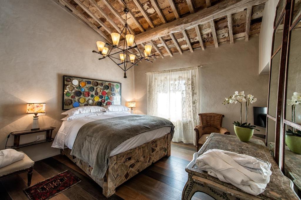 a bedroom with a large bed and a chandelier at Drogheria e Locanda Franci in Montalcino