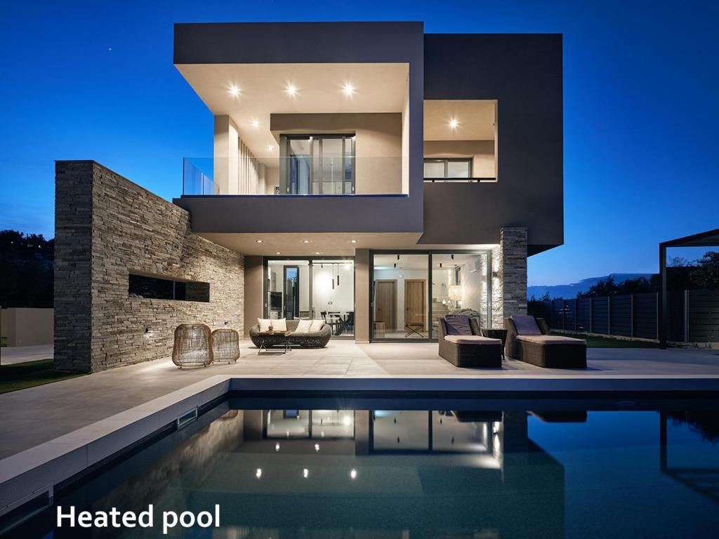 a modern house with a swimming pool at night at Aguacate Ioni in Tsilivi