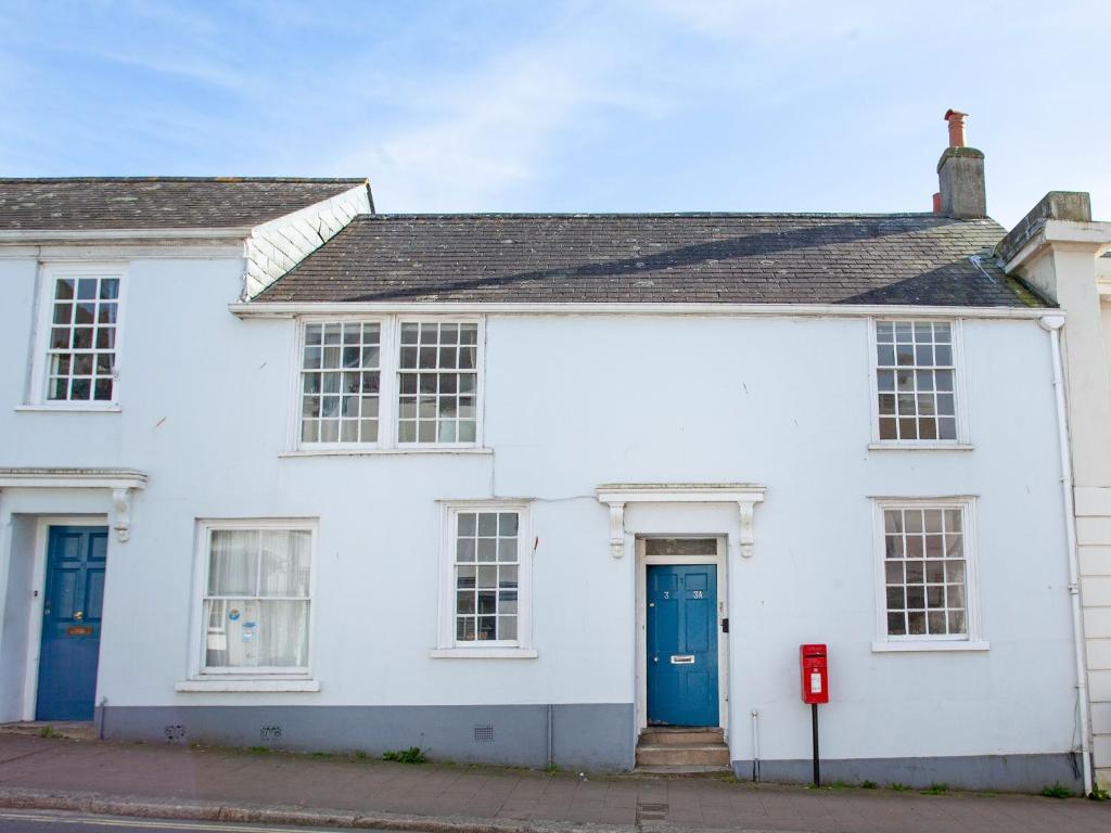 una casa blanca con puertas azules en una calle en Bridgetown, en Totnes