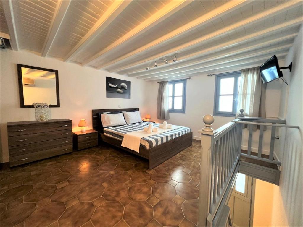 1 dormitorio con 1 cama y escalera con TV en Windmill House Mykonos en Megali Ammos