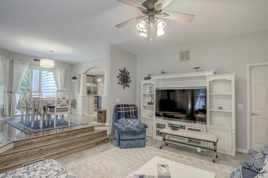 a living room with a ceiling fan and a tv at Lighthouse Seclusion in Ocean Pines