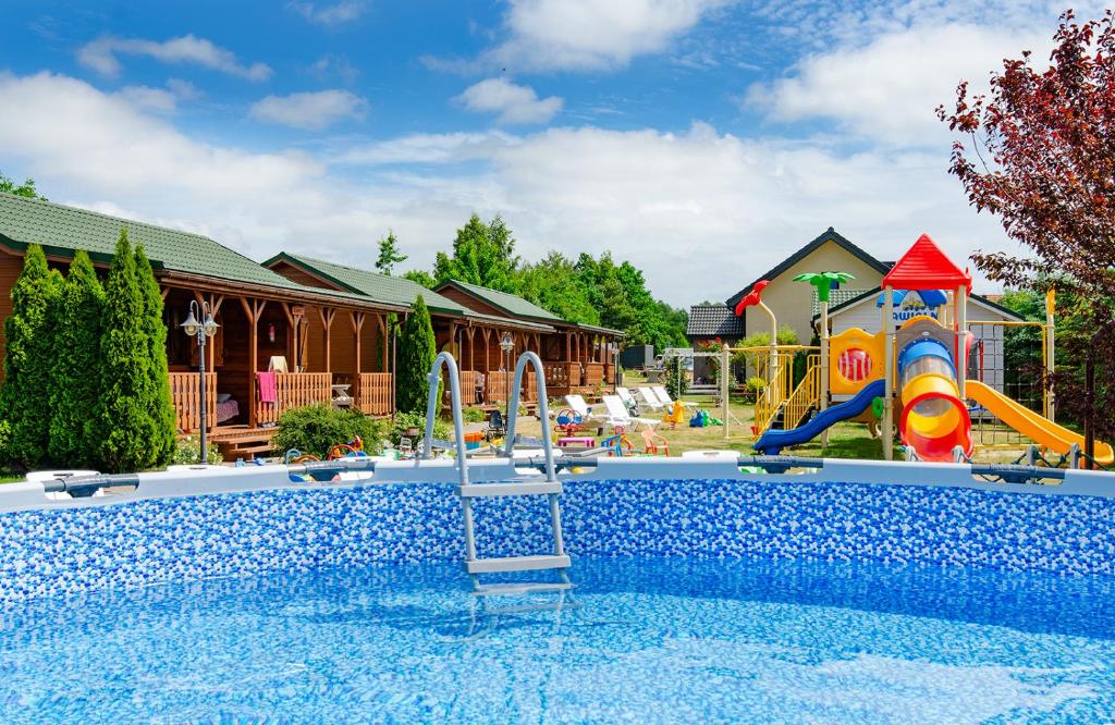 a pool with a slide and a playground at Domki Bartek in Darłowo