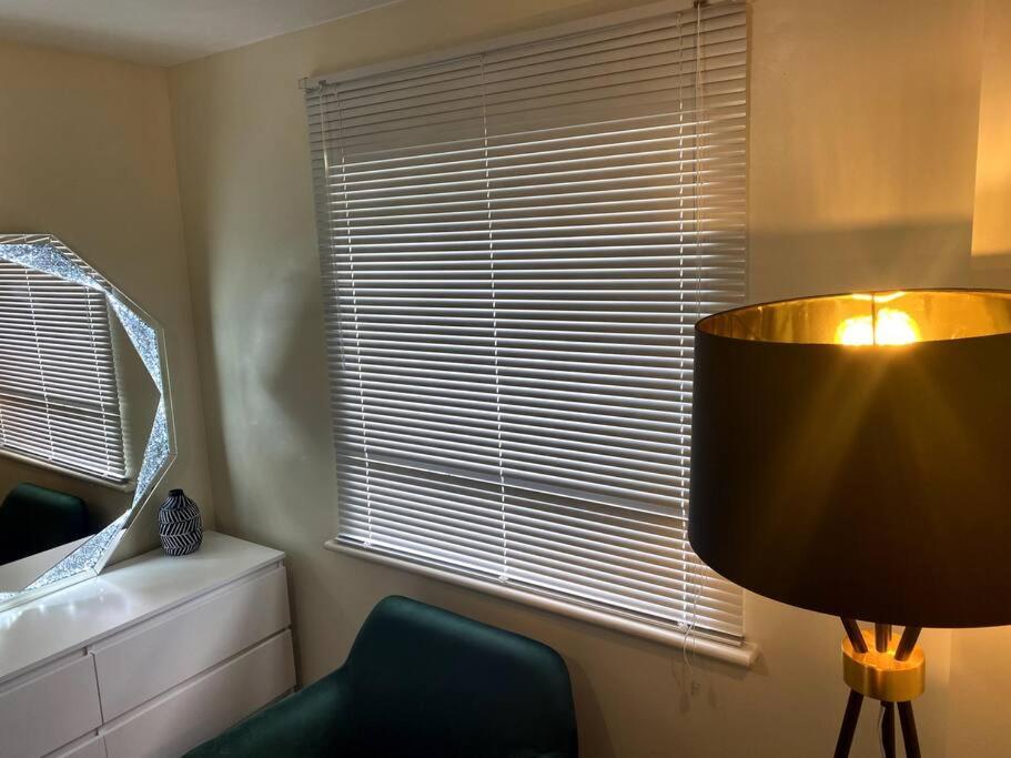 a room with a lamp and a chair and a window at Abbey Wood Luxurious Flat. in Abbey Wood