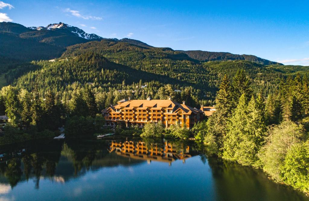 uma grande cabana de madeira num lago nas montanhas em Nita Lake Lodge em Whistler