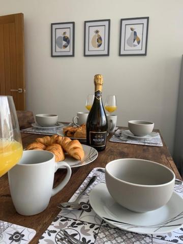 a table with a bottle of wine and some cups and bowls at Plum Tree Corner in Chapel Saint Leonards