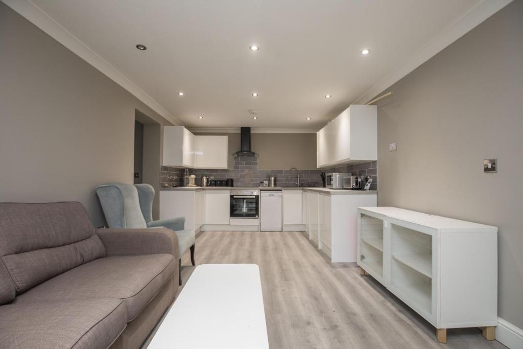 a living room with a couch and a kitchen at Riverside Central Kingston Flat 1B in Surbiton