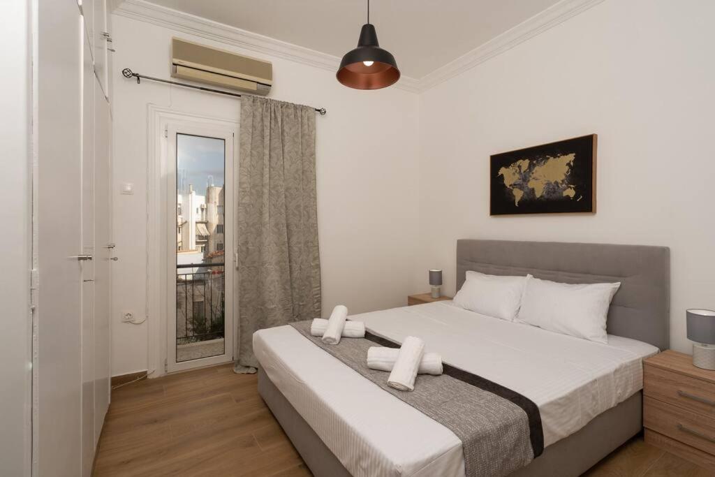 a bedroom with a bed with white sheets and a window at Classy & Comfy 1 BD Apt 4' to Acropolis in Athens