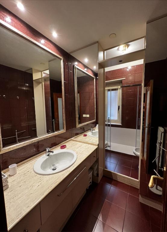 a bathroom with a sink and a shower with mirrors at Appartamento Nonna Carmela in Pescara