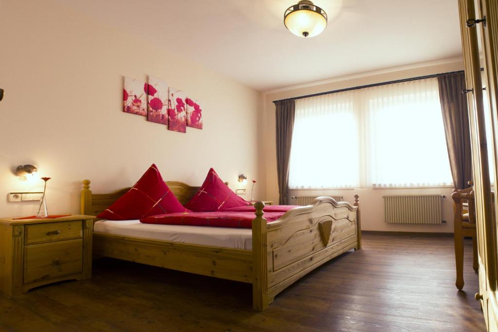 a bedroom with a wooden bed with red pillows at Pension Möser in Lennestadt