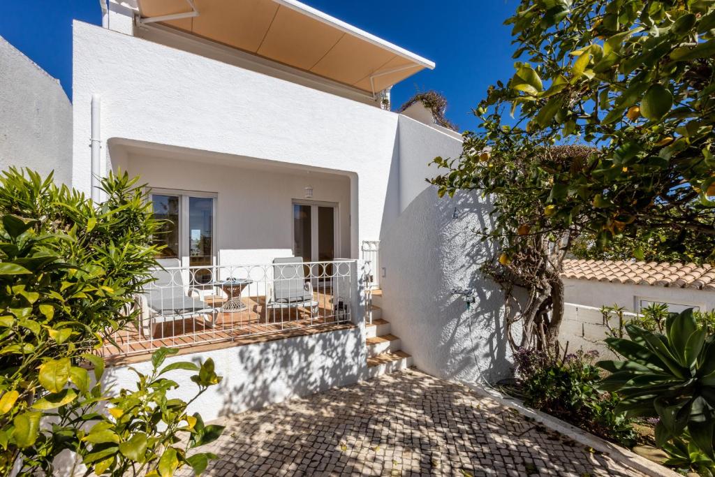 ein weißes Haus mit einer Terrasse und Bäumen in der Unterkunft CoolHouses Algarve Luz, 3 Bed townhouse, lovely sea views, village centre, Casa Limoeiro 54LBC in Luz