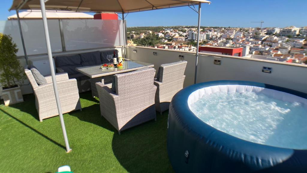 a balcony with a pool and chairs and an umbrella at Apartment Beta - 2 Bedrooms, Private Rooftop Patio with Hot Tub, BBQ and View in Ferragudo