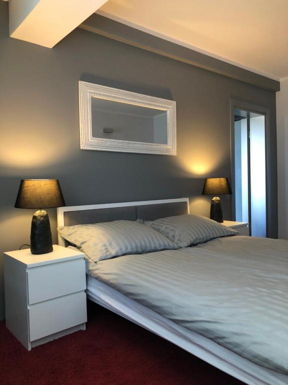 een slaapkamer met een bed met 2 lampen en een spiegel bij Apartament Rezydencja Przy Młynie in Gorzów Wielkopolski