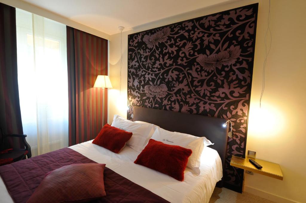a bedroom with a bed with two red pillows at Hotel La Chaumiere in Dole