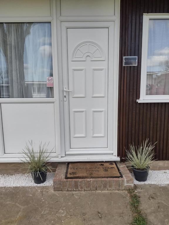 a white door on a house with two potted plants at 19 Seadell in Hemsby