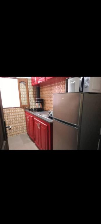 a kitchen with a stainless steel refrigerator and red cabinets at Angelus Meublés 