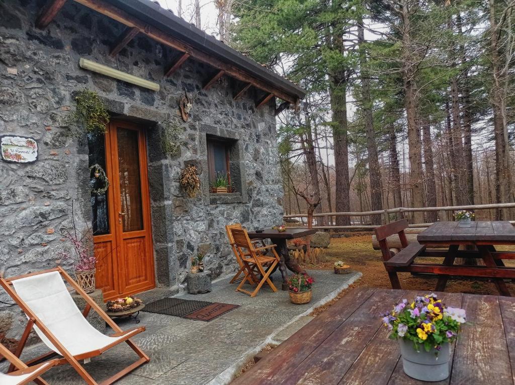 Ce cottage en pierre dispose d'une porte en bois et d'une table de pique-nique. dans l'établissement Bosco Magaudo - Casa U Parmento, à Linguaglossa