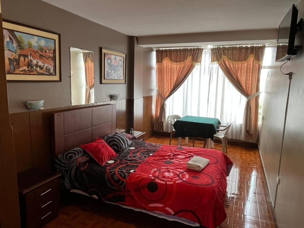 a bedroom with a bed with a red comforter at Hotel Cotopaxi in Latacunga