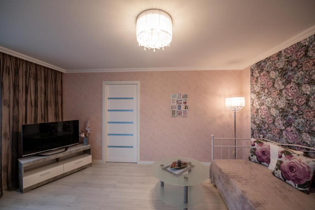 ein Wohnzimmer mit einem Sofa und einem TV in der Unterkunft LULU APARTAMENT in Ventspils