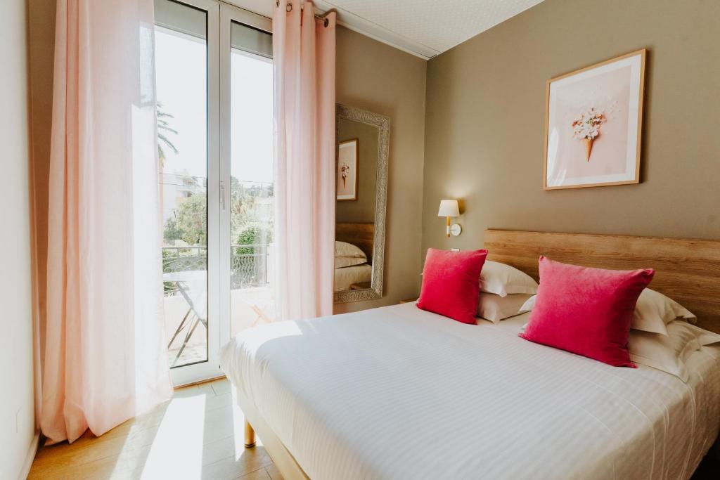 um quarto com uma cama grande e almofadas cor-de-rosa em Hôtel Le Petit Castel em Antibes