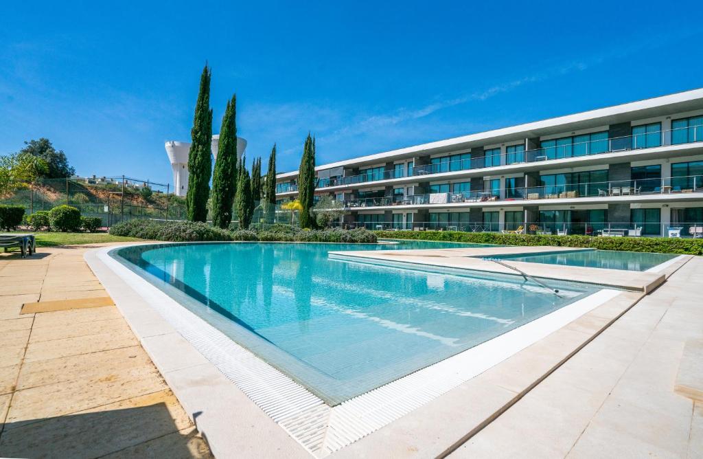 a large swimming pool in front of a building at 1 Bed With Balcony Pool and Tennis in Quarteira