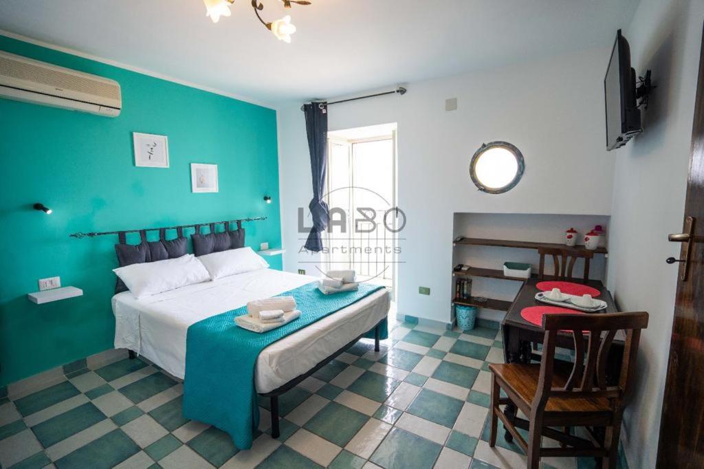 ein blaues Schlafzimmer mit einem Bett und einem Tisch in der Unterkunft Choros in Tropea