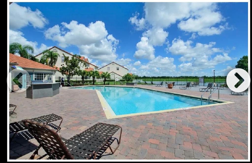 a swimming pool with chairs and a house at Deluxe Stays in Kissimmee