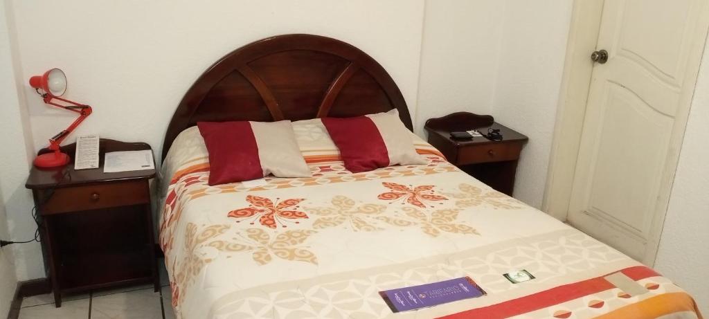 a bed with a wooden headboard in a room at Hostal Almagro in Quito