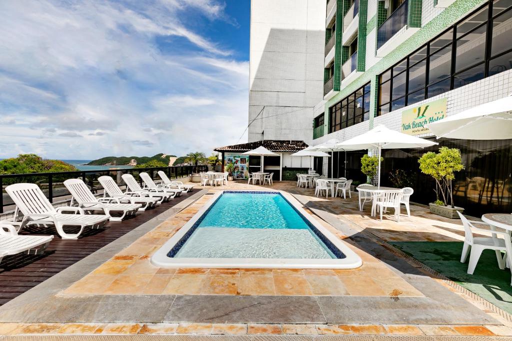 una piscina en un edificio con sillas y mesas en Yak Beach Hotel Ponta Negra, en Natal
