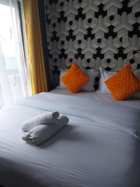 ein Schlafzimmer mit einem Bett mit orangefarbenen und weißen Kissen in der Unterkunft DG's Suites in Nairobi