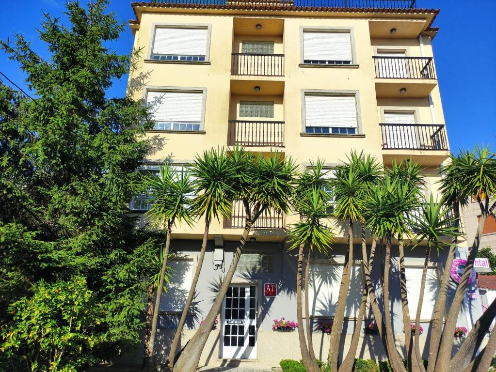um edifício com palmeiras em frente em Apartamentos Sanxenxo Progreso 140 em Sanxenxo