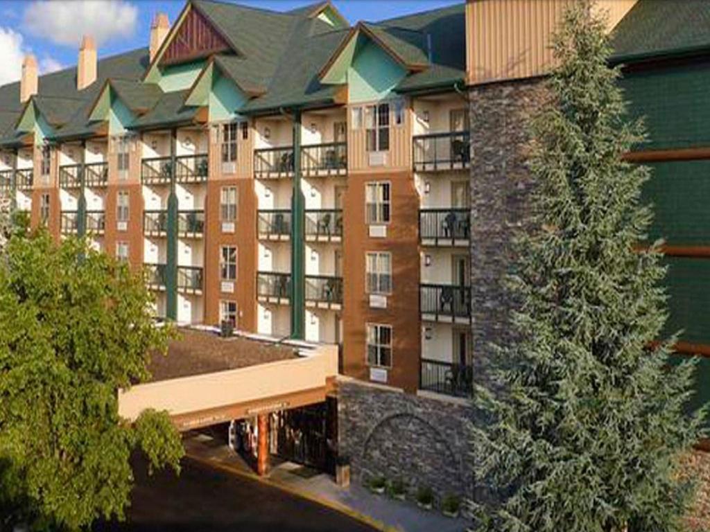 鴿子谷的住宿－Grand Smokies Resort Lodge Pigeon Forge，一座大型公寓楼,前面有一棵树
