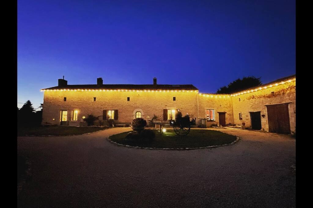 un gran edificio de ladrillo con luces encendidas por la noche en Spacious & Characterful 6 Bed Farmhouse with Pool en Vanzay