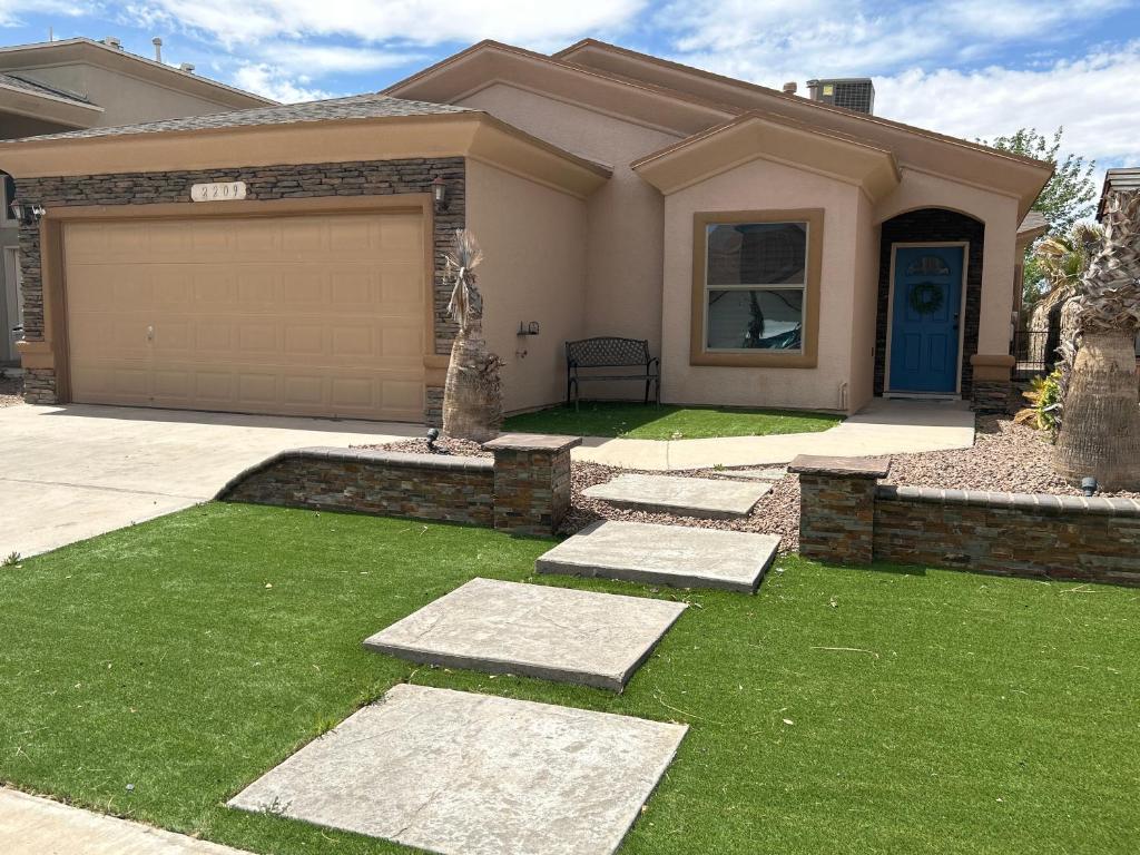 a house with a garage and green grass at Hidden Gem Cozy Home MiCasa TuCasa in El Paso